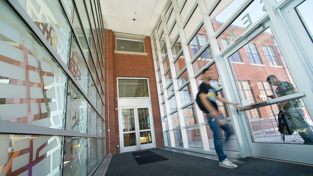 a student walks through the glass hallway of the Student Support Services building at JWU 