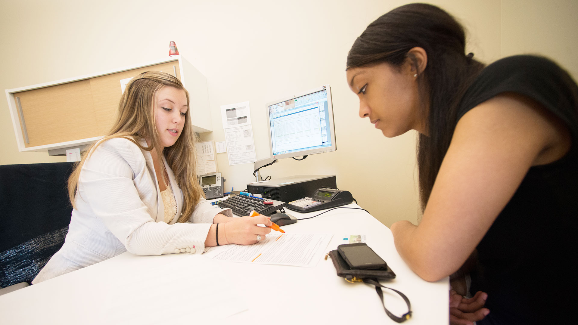 a female financial planner and a female student work together on paperwork