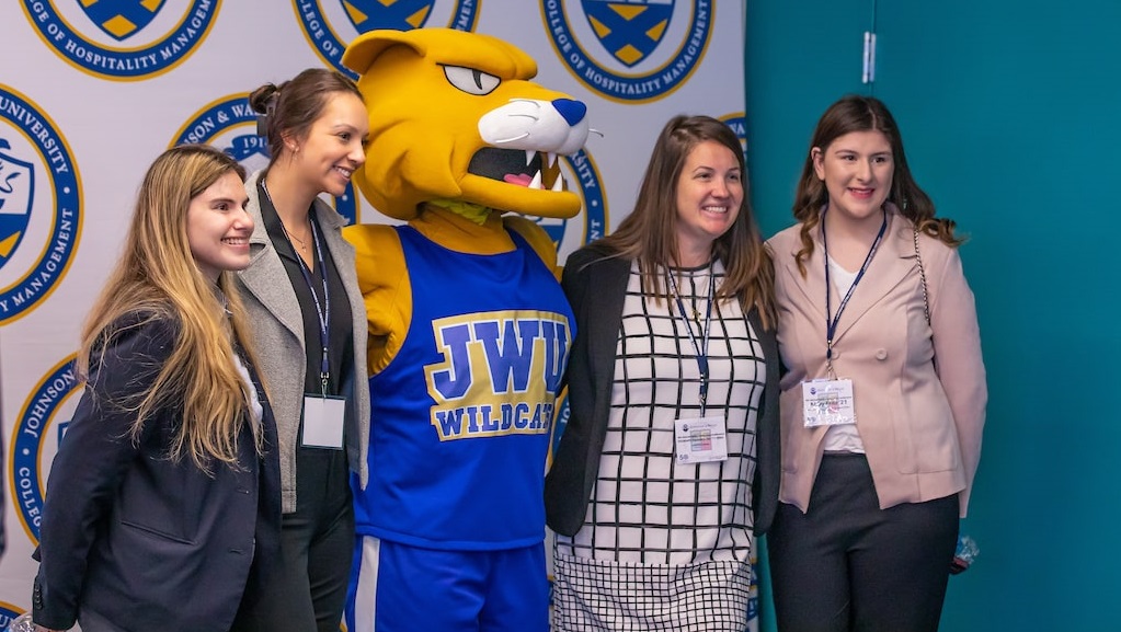 Student gather with Wildcat Willie behind the scenes at the conference