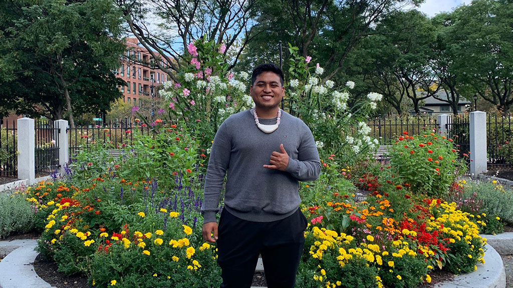 photo of Xavier Quinata posing with a smile in front of flowers and trees