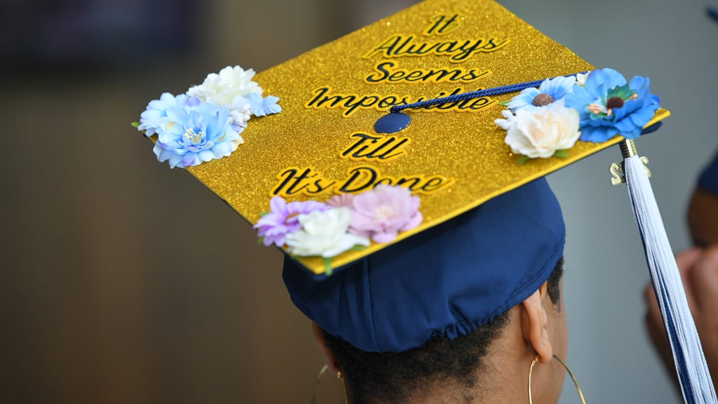 A decorated mortarboard reading, “It always seems impossible ’til it’s done.”