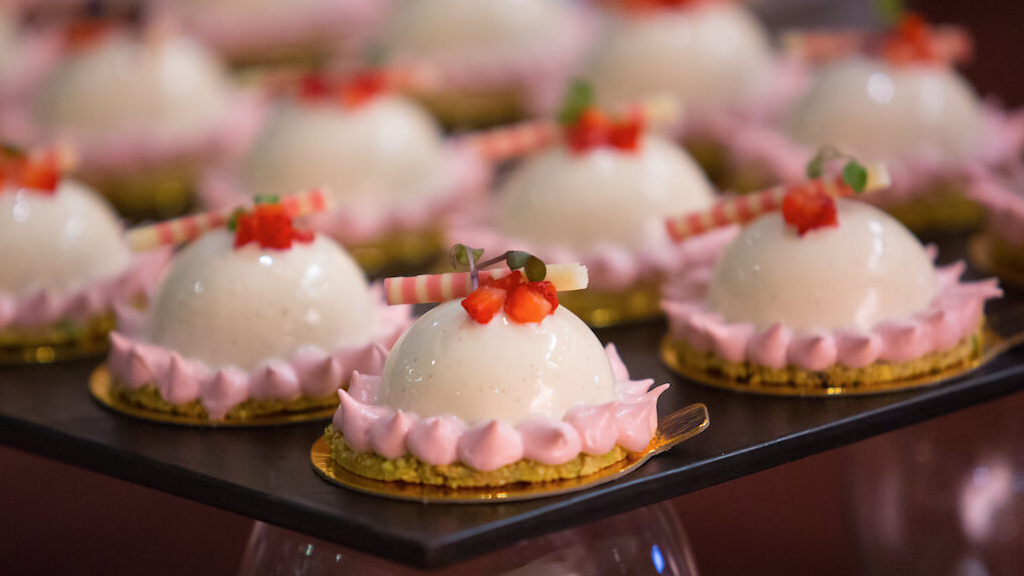 pink, white, and red pastries aligned in a tray