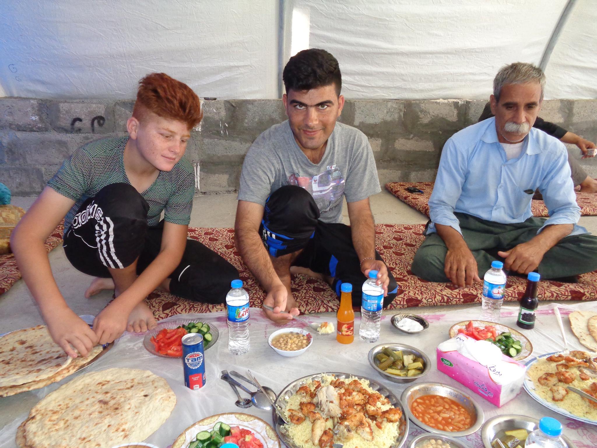 Iraqi Kurdistan Habib serves a family feast in a refuge camp with Associate Professor Kevin DeJesus as his guest