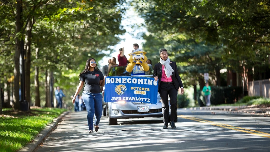 JWU students holding a Homecoming Charlotte banner 