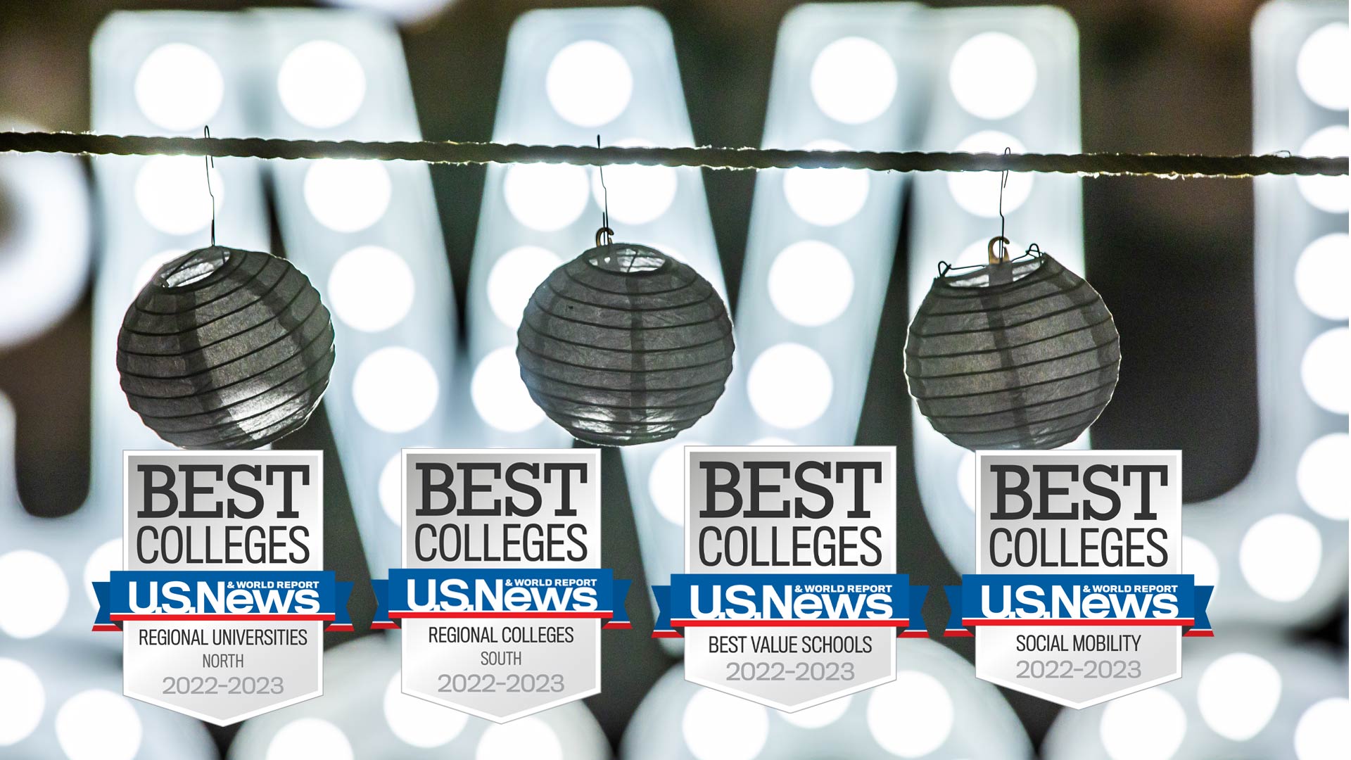 photo of four U.S. News Best Colleges badges in front of JWU lit up in lights