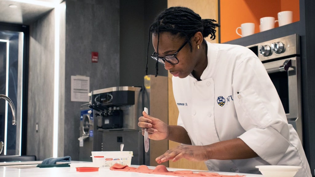 JWU Providence student Antoinnea Stubbs assembling heart-shaped ravioli from two thin sheets of pasta.