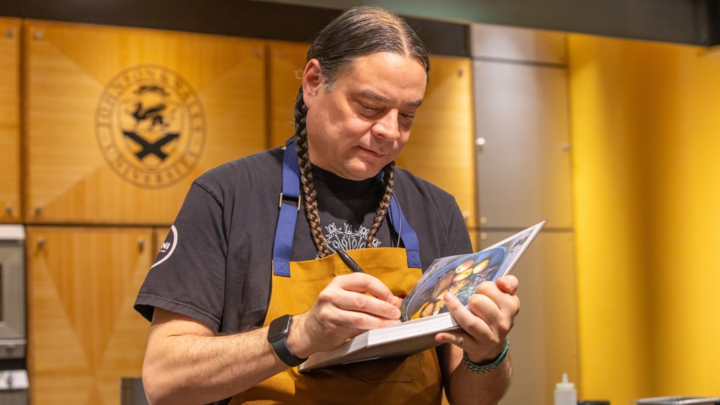 Sean Sherman signing a copy of this book, “The Sioux Chef’s Indigenous Kitchen.” 