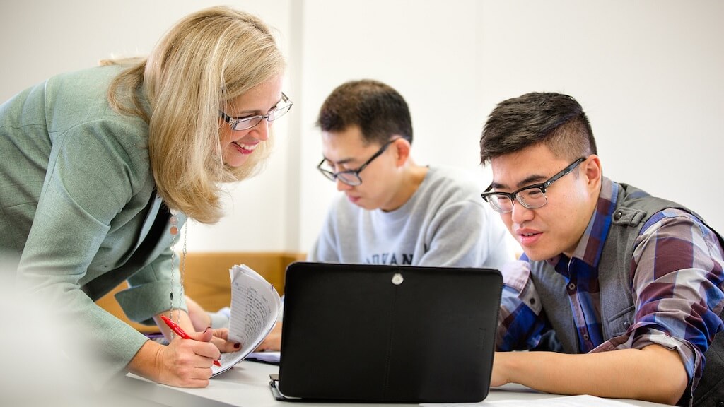 Teacher assisting student on laptop