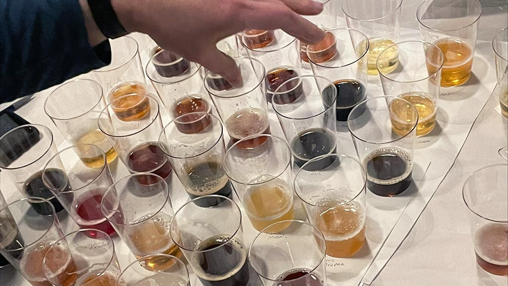 a photo of small cups each containing different colored beers to be sampled at the competition
