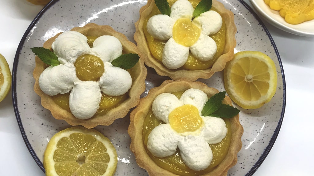 Plated lemon tartlets with whipped cream topping.