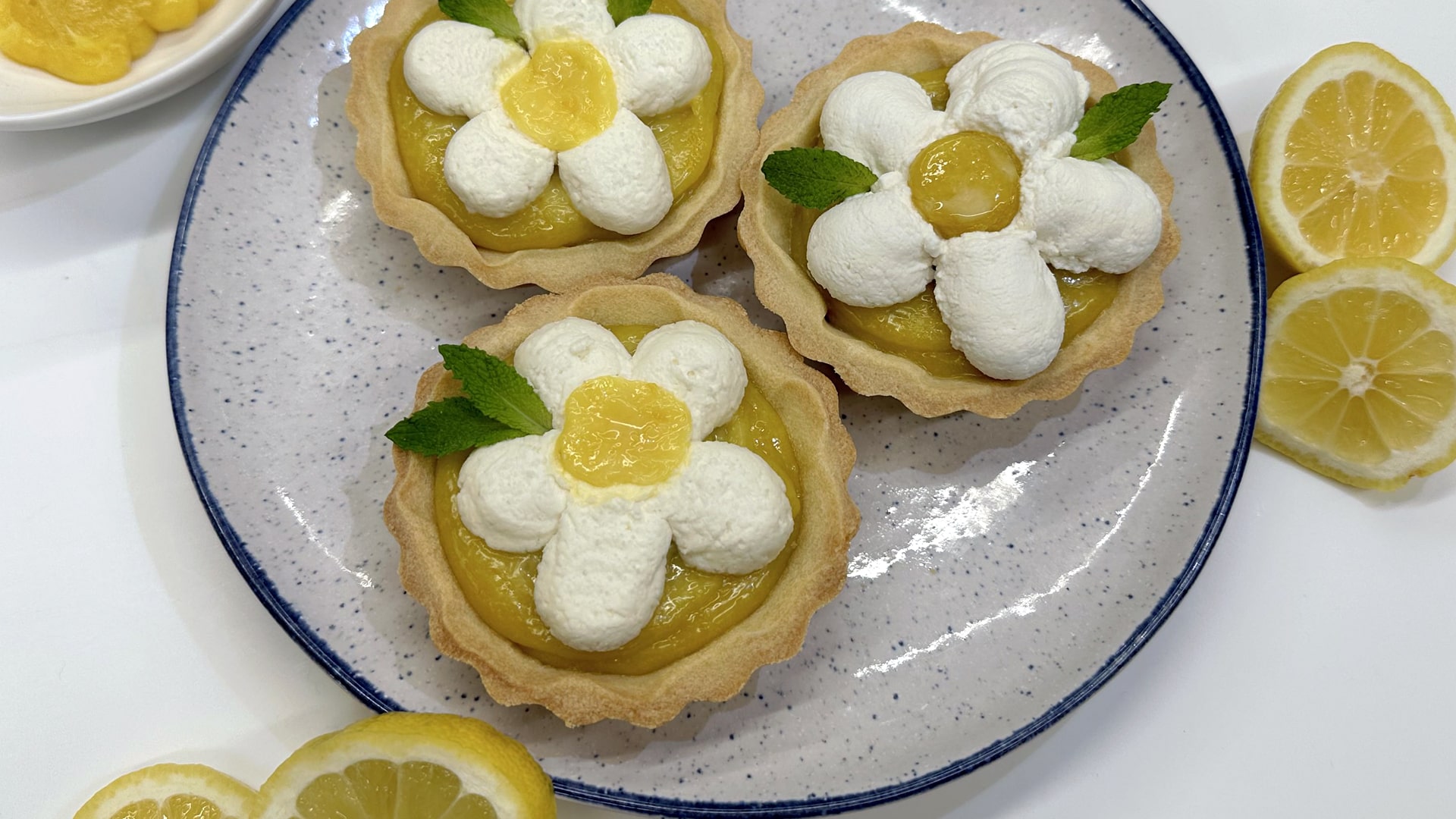 Lemon tartlets surrounded by an assortment of cut and whole lemons.