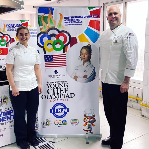 Young Chef Olympiad contestant Chantelle Gonsalves (left) and chef-mentor Jeremy Houghton (right) flank a promotional standee for Team USA.