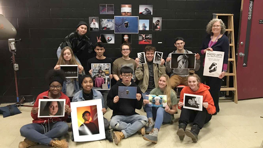 A group of students each holding up their design work