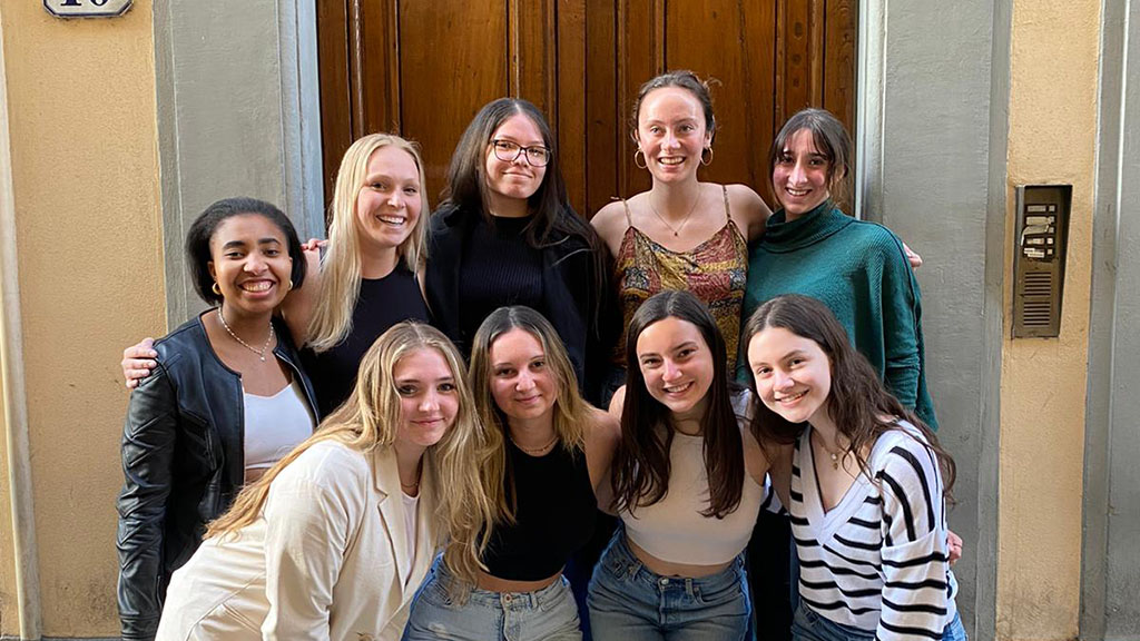 Nine students standing together in front of a door