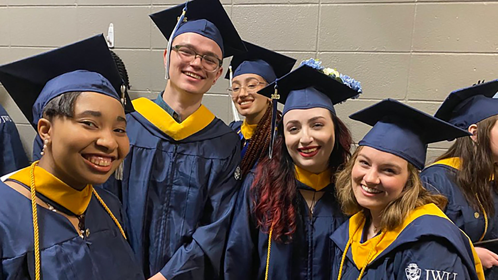 Five JWU students smiling in their graduation caps and gowns