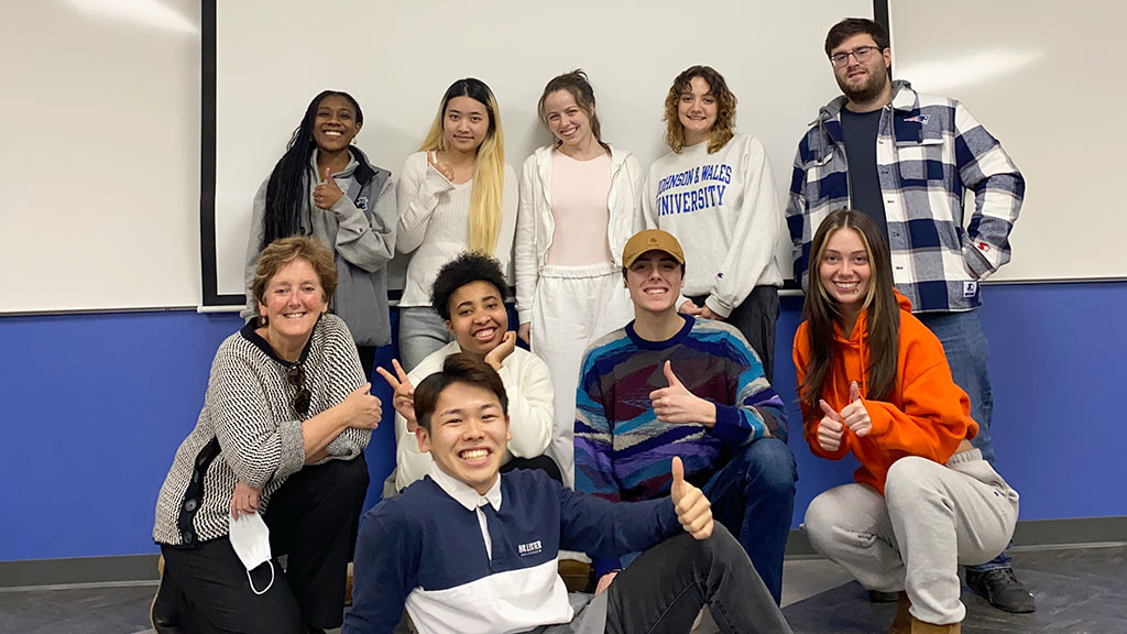 Students posed together in a classroom in front of the whiteboard