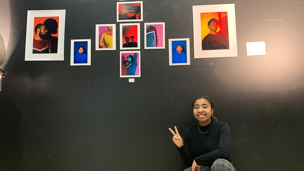 Student Leah Ward '23 in front of her wall of designs