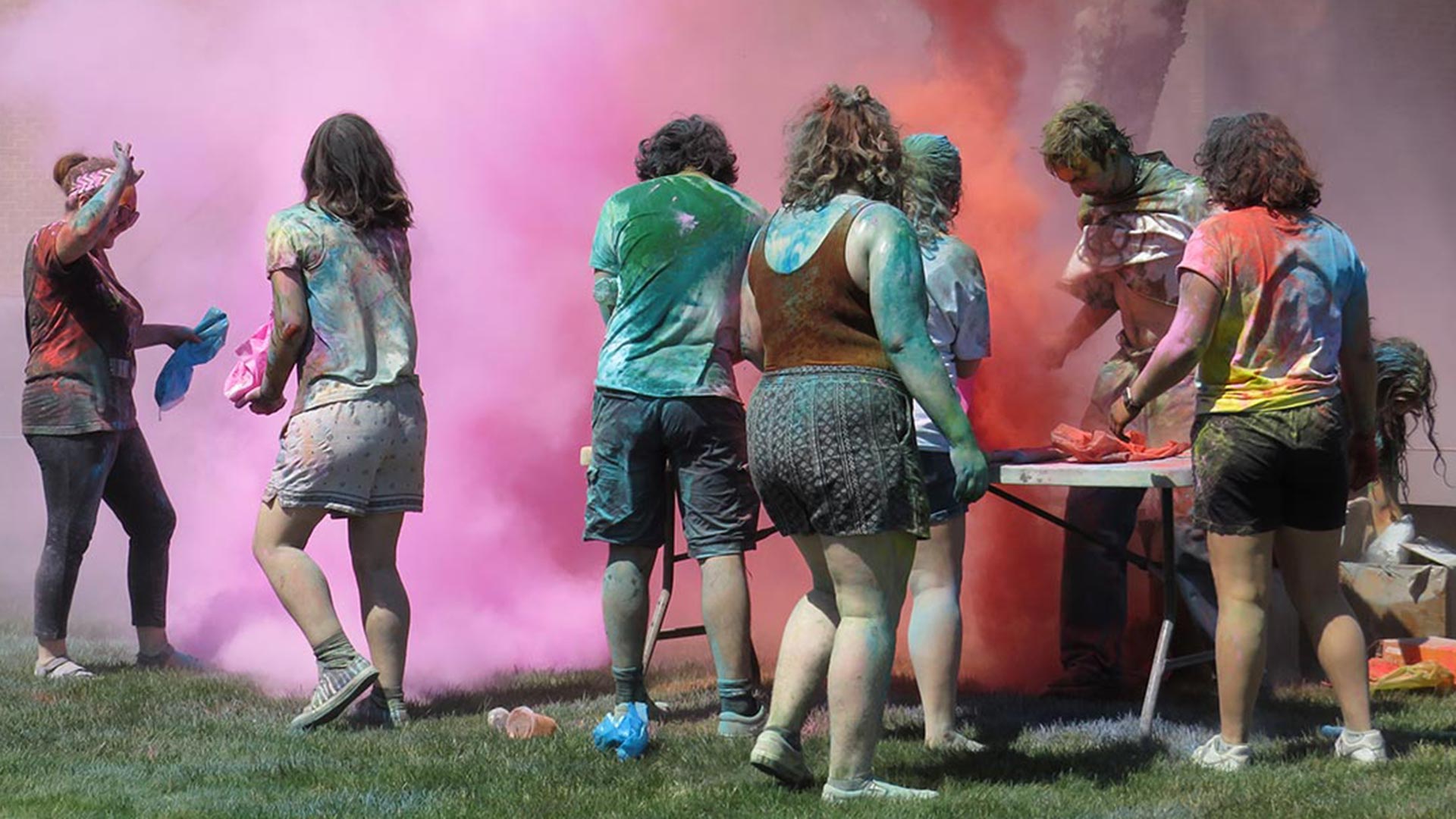 photo of a group of students under a cloud of colored chalk in the air