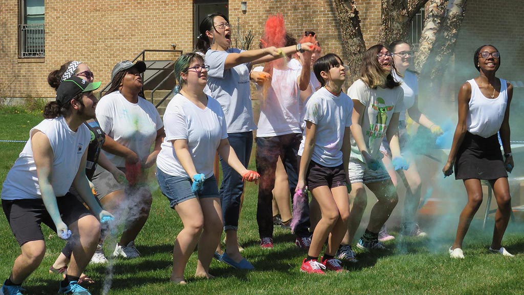 group of college students preparing to throw colored chalk