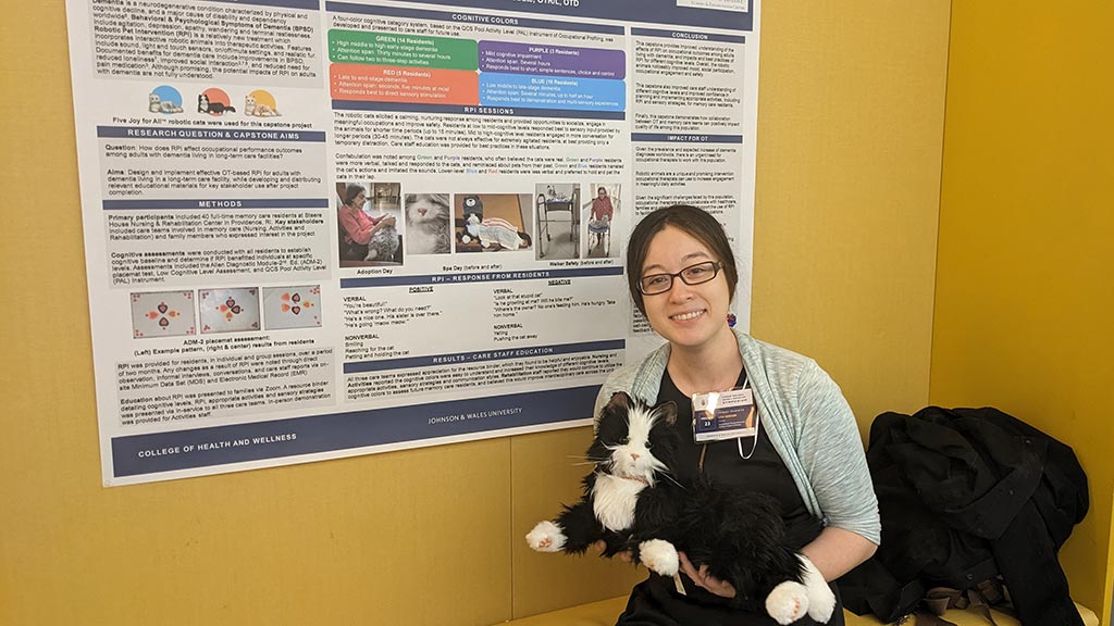 OTD student Lisa Benson '23 poses with one of the robotic animals she used for intervention for patients with dimentia