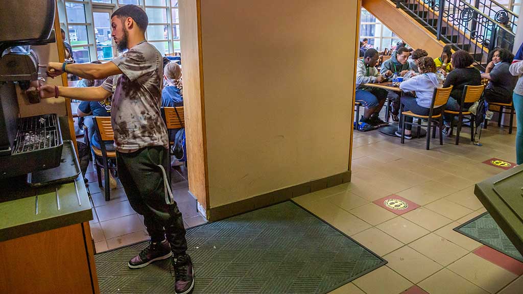 A student selects a beverage in the foreground while others dine at Snowden Hall on the Providence Campus