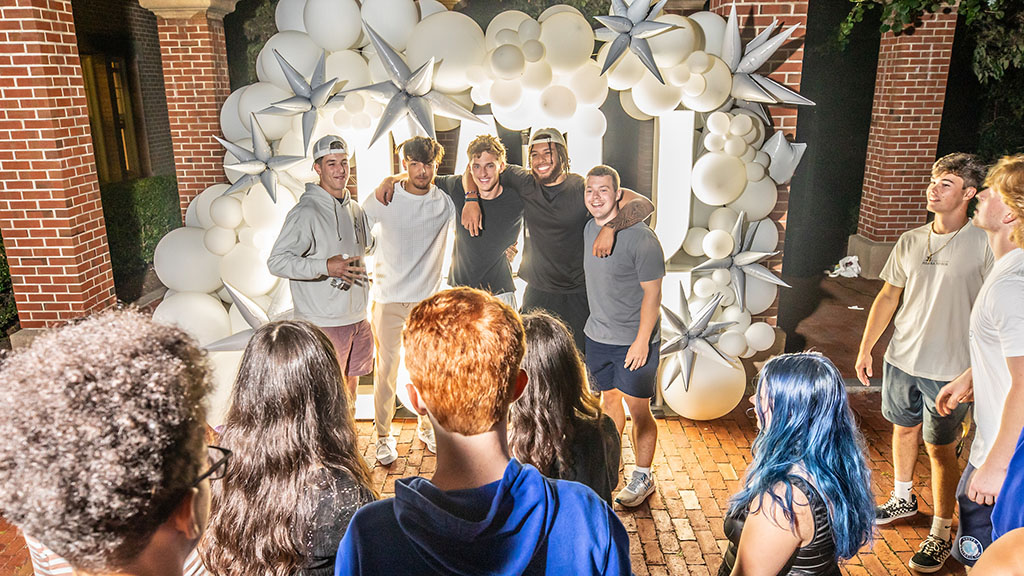 Students posing in front of balloons and lights at Ignite the Night