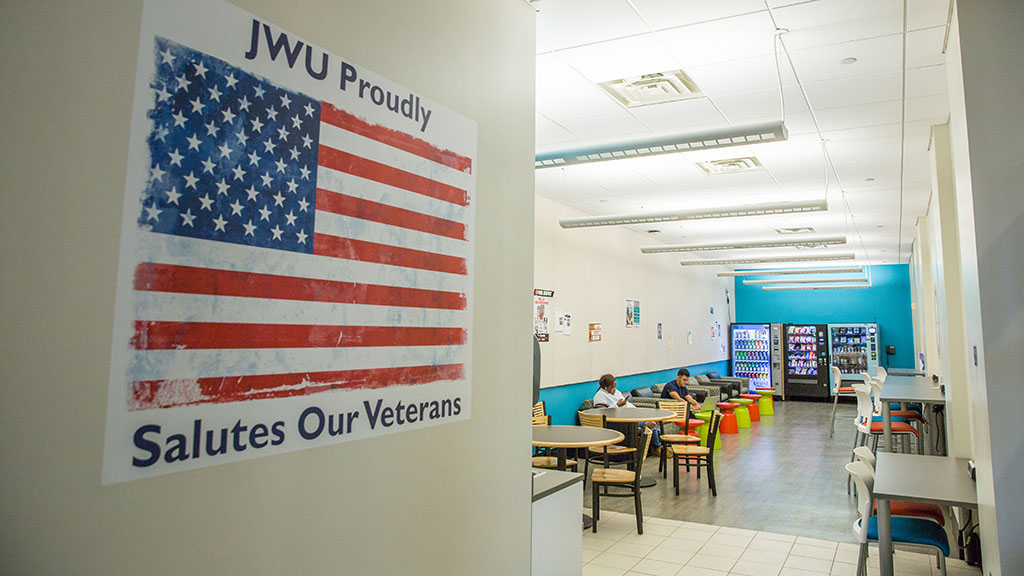 a photo showing a large "JWU Proudly Salutes Our Veterans" poster on a wall on JWU's Charlotte Campus