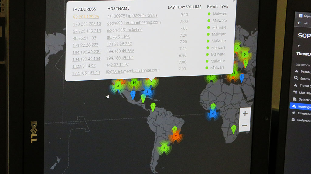 a photo shows a closeup of a computer monitor displaying a map of the world where cyber attacks are happening and a list of IP addresses