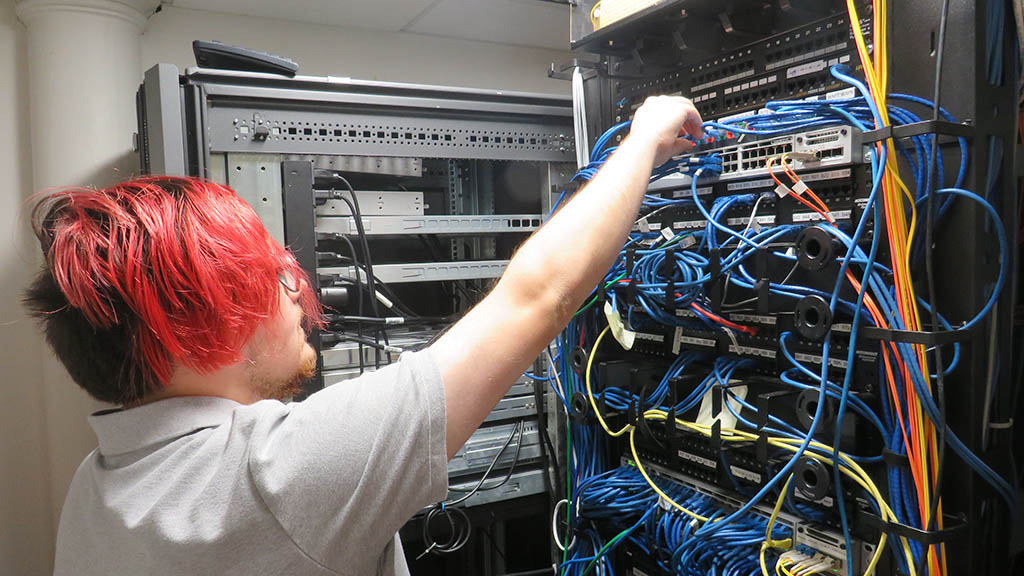 an action photo of student employee Alex Mullin working in the server room