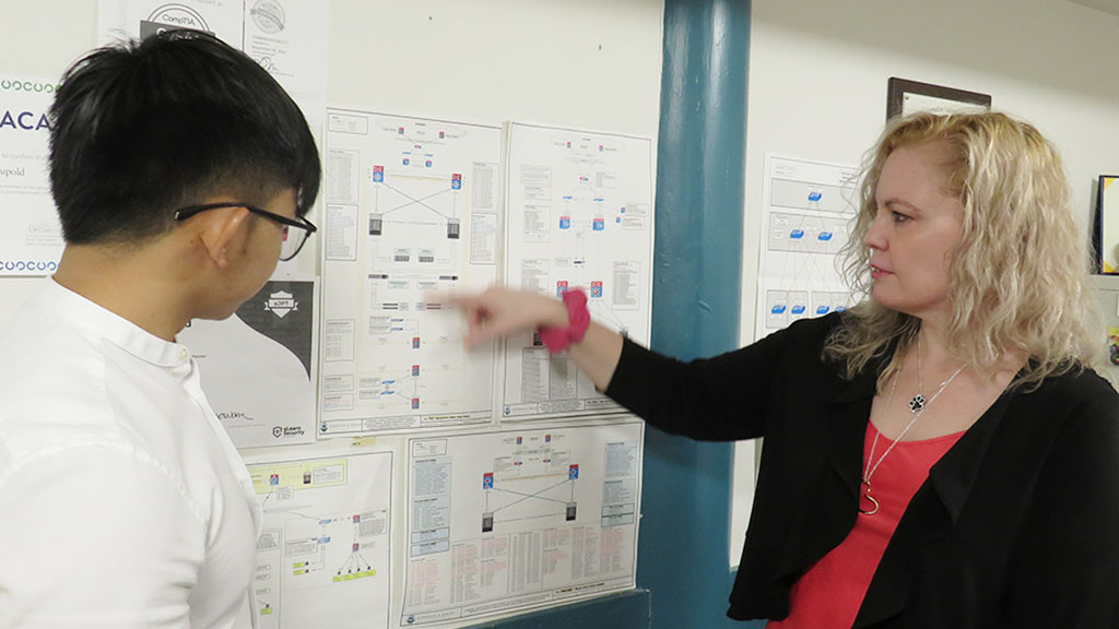 a photo of Mary Ide pointing out something to student employee Sing Khun '24 from some charts taped to the wall