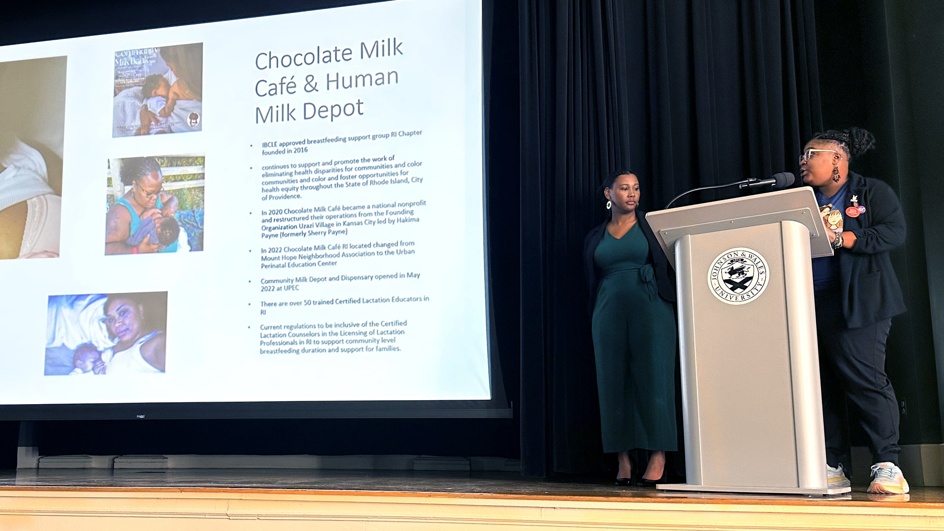 Kaitlyn Rabb, the policy analyst for Rhode Island KIDS Count, and Quatia “Q” Osorio, the executive director of the Urban Perinatal Education Center, in front of a slide about community-led childbirth and postpartum education.