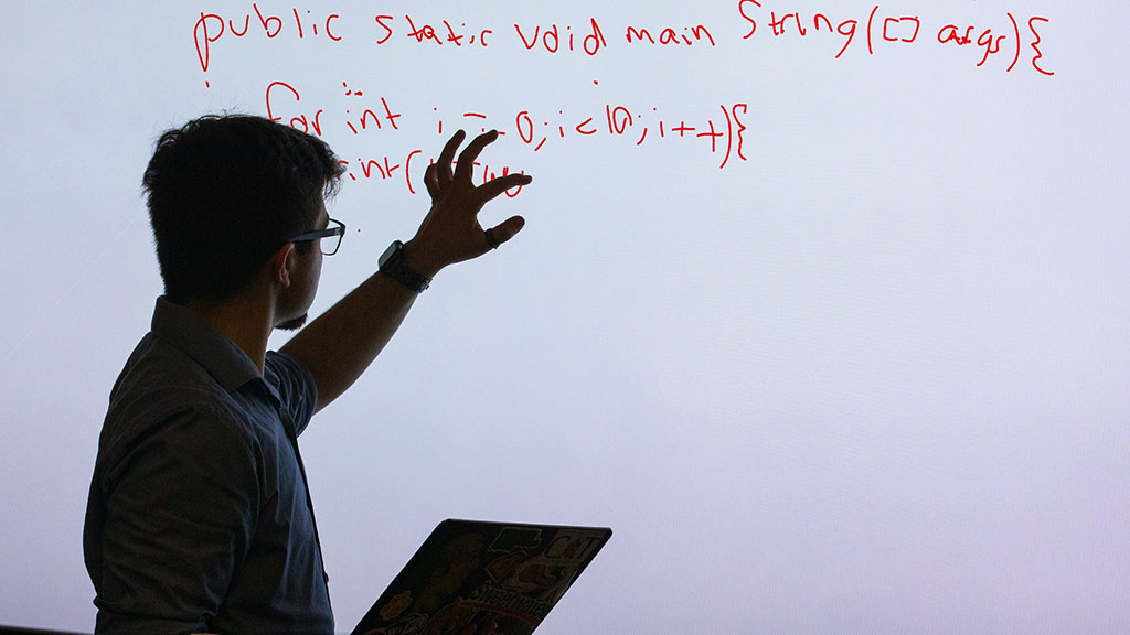 a photo of Jae Grenier '23 demonstrating some code on an overhead screen