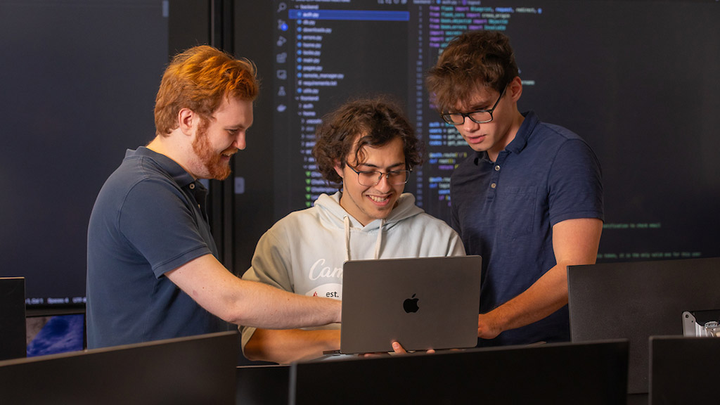 CyberPaw student development team look at computer screen together.