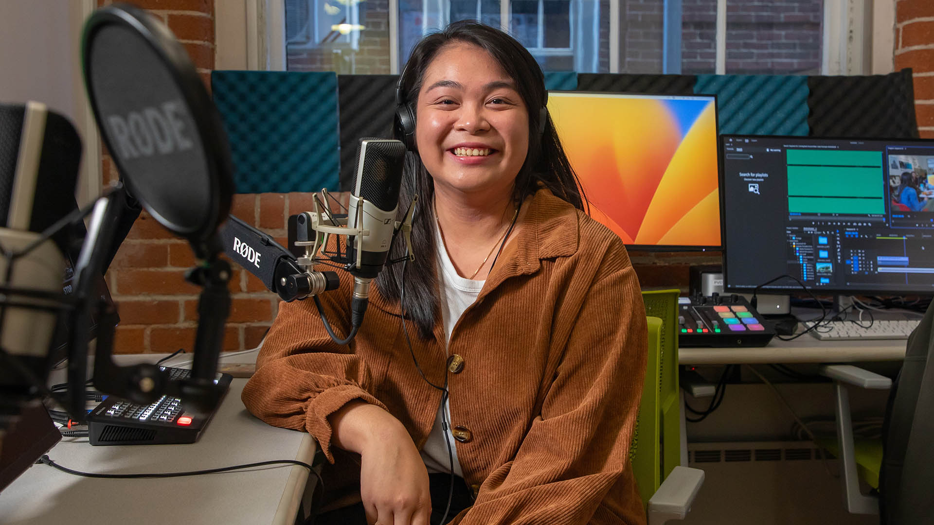 photo of Hillary Thilavong '23 smiling from behind the microphone in the Center for Media Production