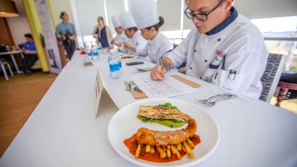 Cooper Leming's dish sits in the forefront as judges in the background takes notes during the Future Food Competition