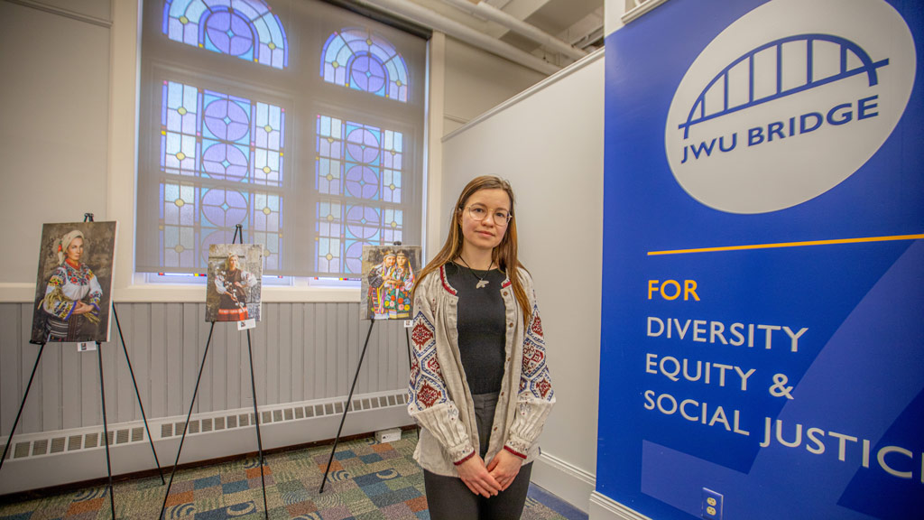 a woman stands in the forefront of artwork on easels in JWU's Bridge Center