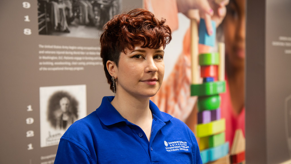 photo of Molly Gould OTD '24 in front of a timeline graphic in the OTD program space