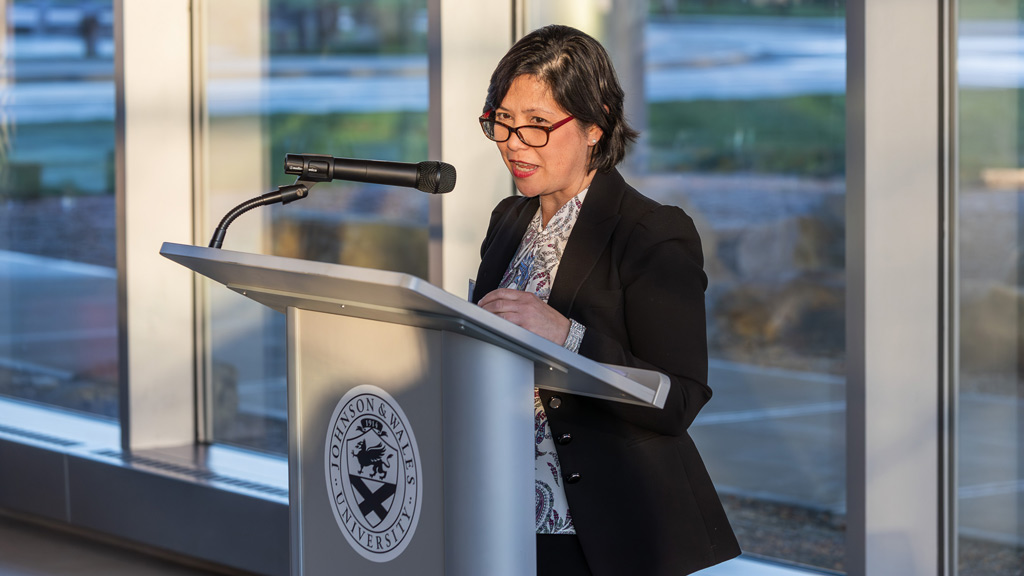 photo of Director of Alumni Relations Marie-Ines Valdepenas speaking at a podium