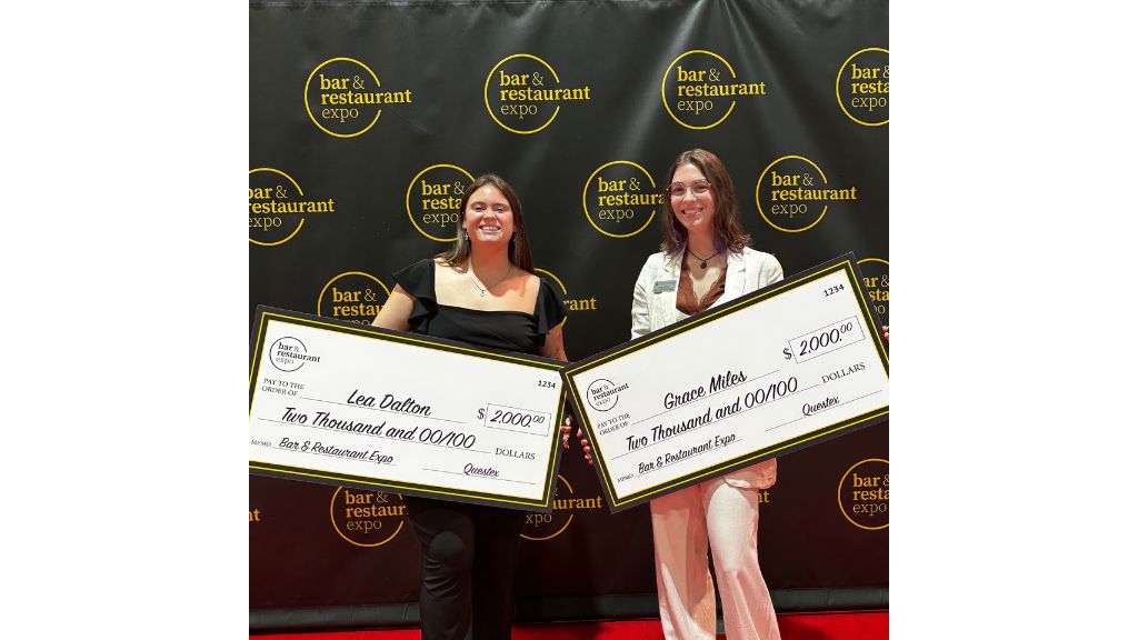 photo of Lea Dalton '26 & Grace Miles '26 holding large checks