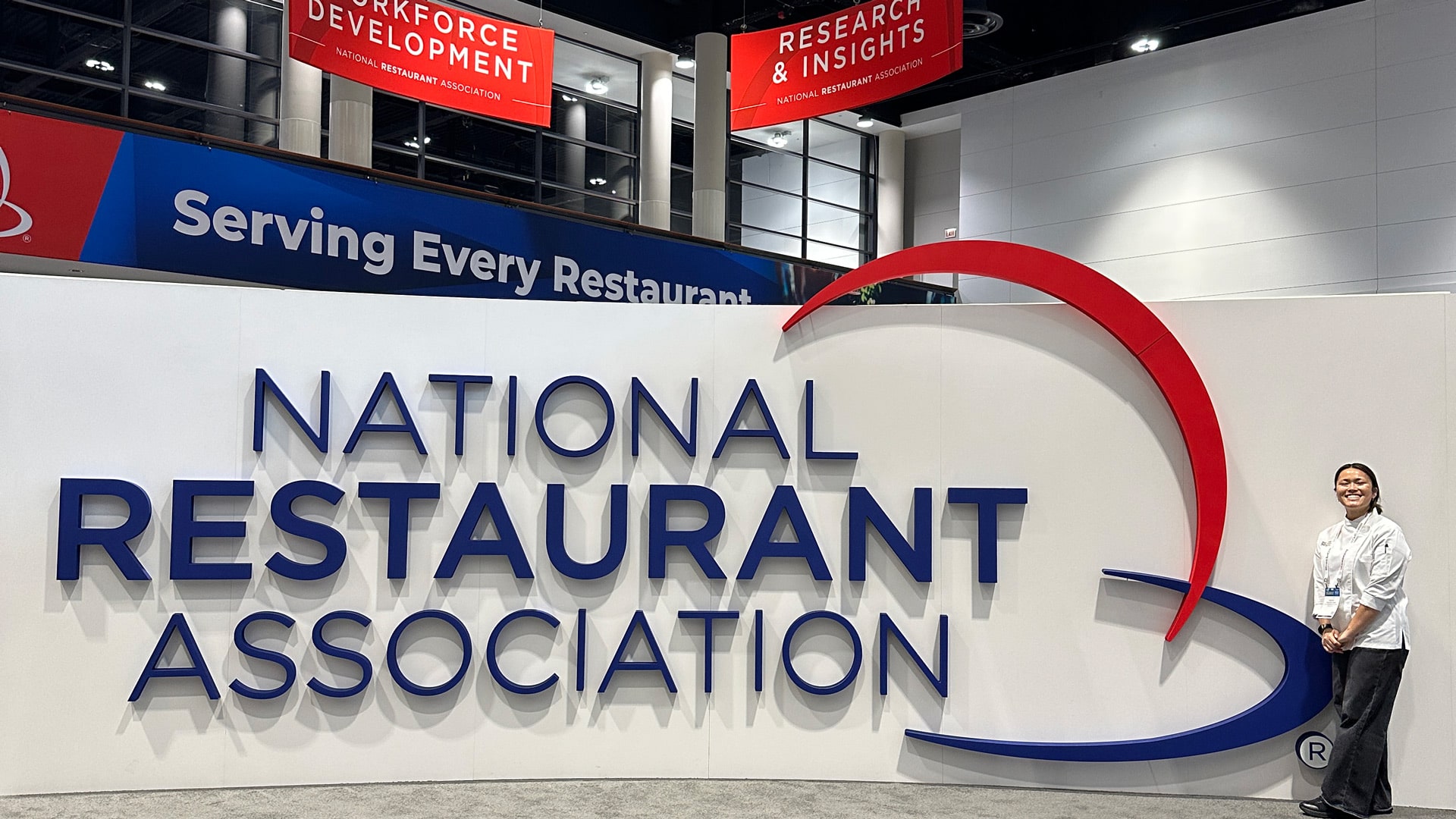 a photo of Madison Chan '26 posing with a giant National Restaurant Association sign