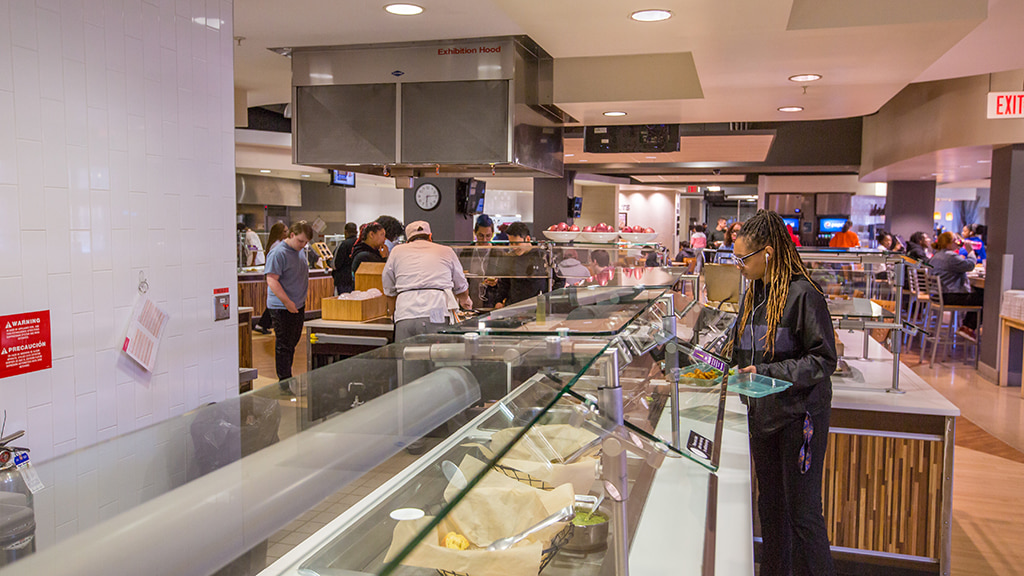 Student puts food into a reusable container at a dining hall
