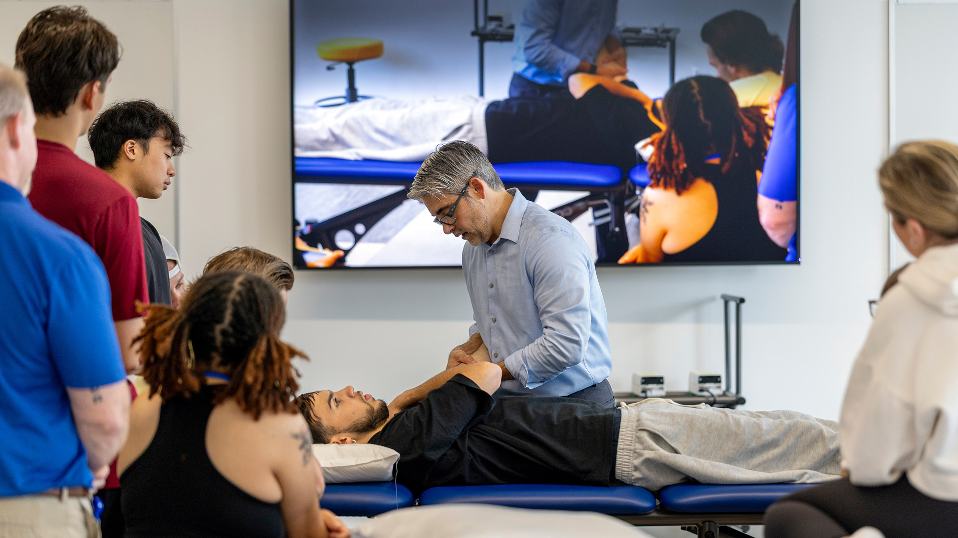 Assistant Professor Kevin Pozzi works with students in a PT lab.