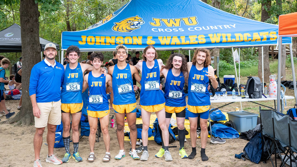 The JWU Charlotte Men’s Cross-Country team poses with their coach, Dustin Stewart (far left).