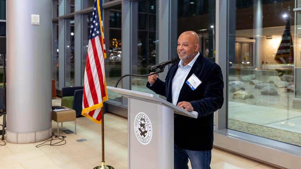 George L. Ortiz standing at a podium speaking