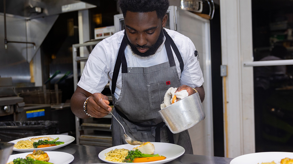 Chef Nol Foretia  '16 prepares meals of fish, pasta and veggies