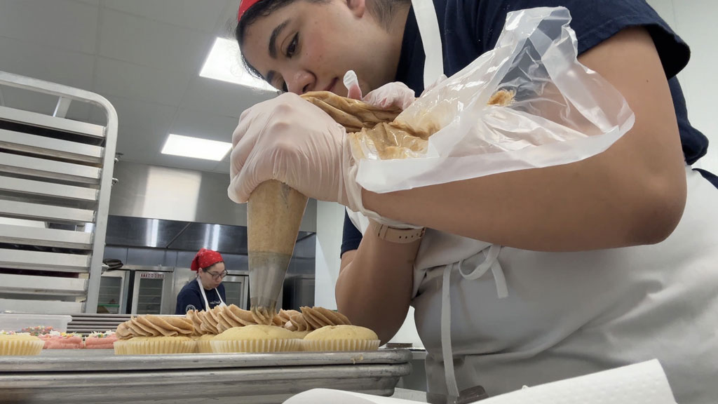 Briana Torres '26 frosting mocha chocolate cupcakes.
