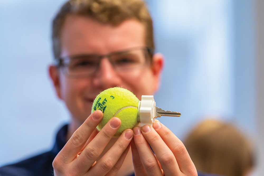 A student hold a prototype for a product designed to ease using keys