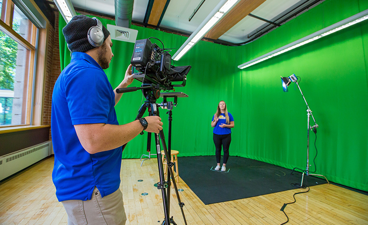 Student filming another student in front of a green screen