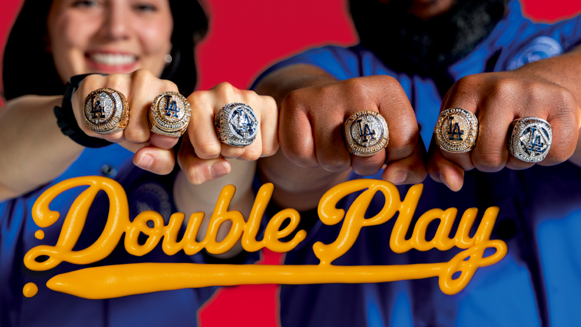 A woman and man holding hands out wearing LA championship rings with the words Double Play written below