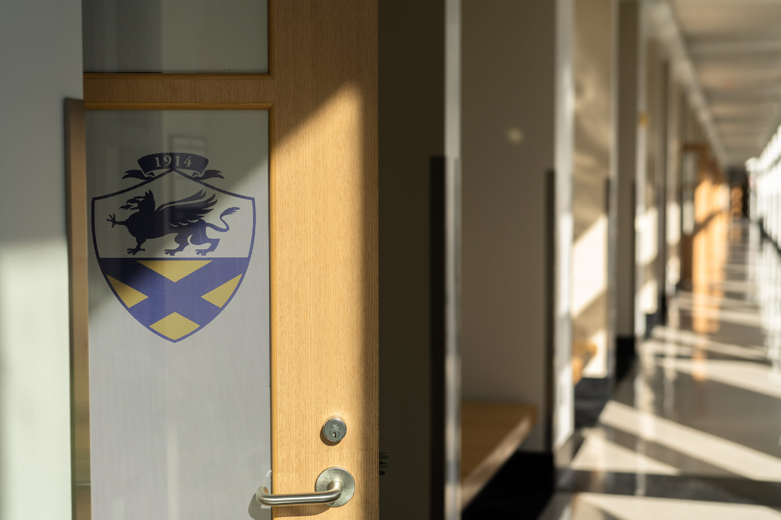 Open door with JWU logo in long sunlit corridor